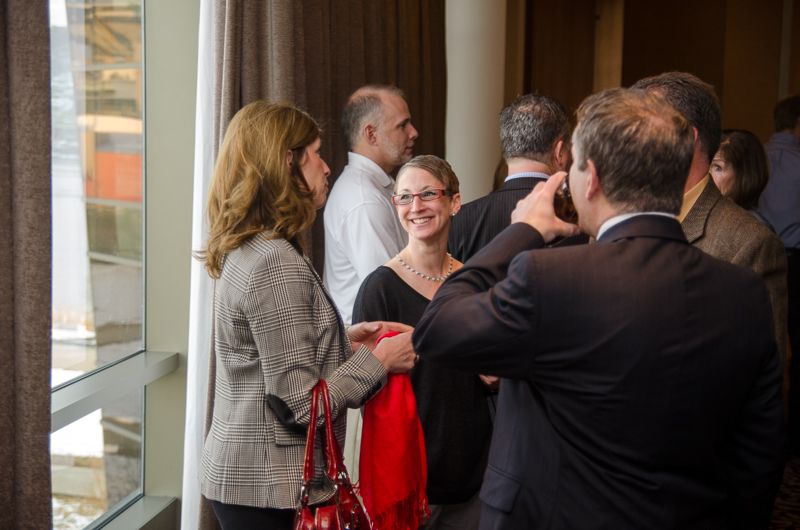 Professionals talking by a tall window at an after-work happy hour