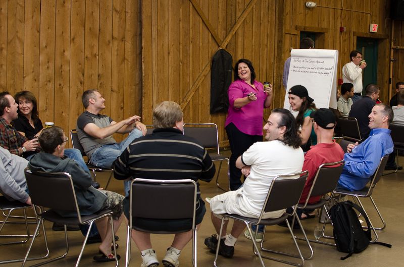 Colleagues sitting in a circle of chairs laughing during a brainstorming session