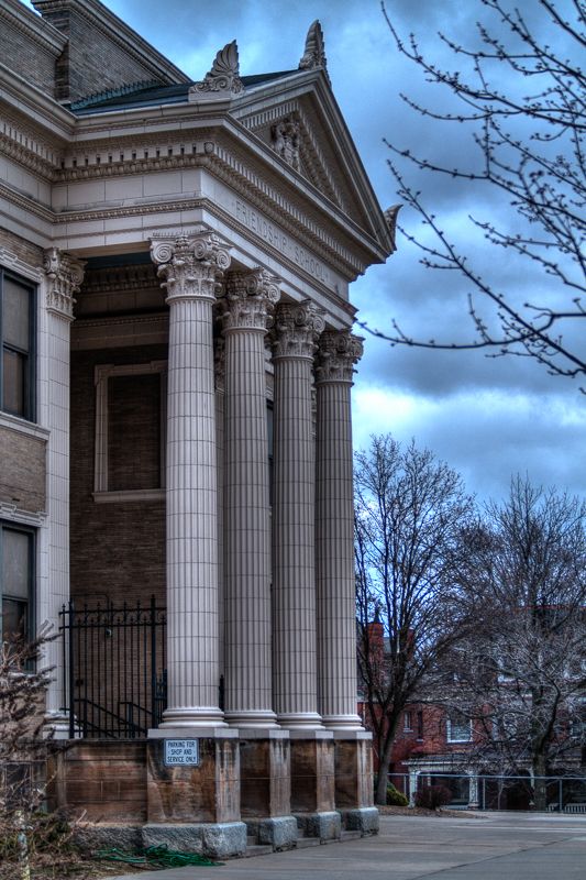 The Corinthian-columned portico of a historic school building under a dramatic evening sky
