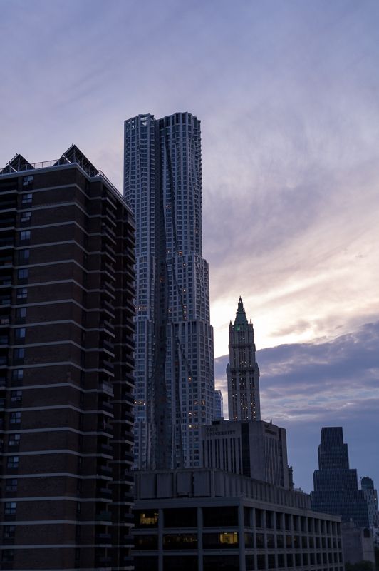 Lower Manhattan towers, including the rippled steel of 8 Spruce Street, against a pink evening sky